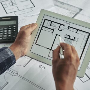 cropped-view-male-hands-holding-digital-pad-examining-blueprint (1) (1)